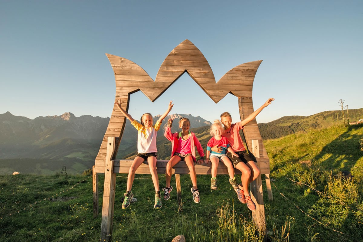 Kinder auf einem Riesenbanklerl mit dem Hochk&ouml;nig Logo
